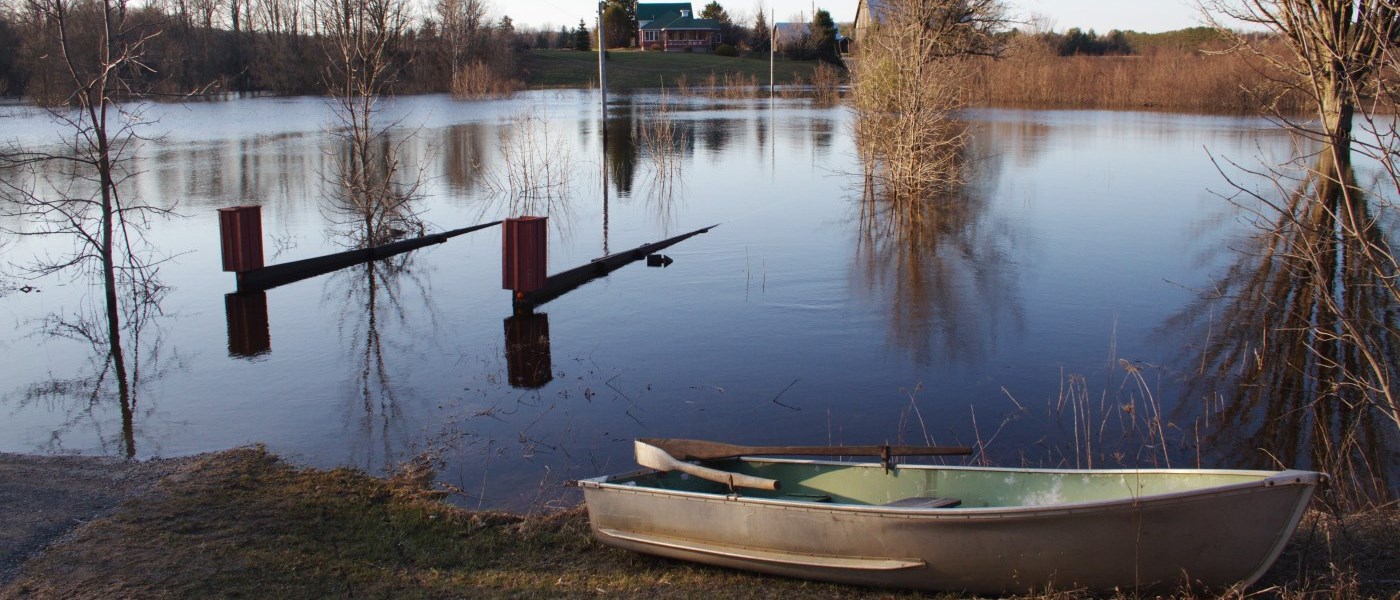 flooded bridge with a boat in the foreground and a house in the background