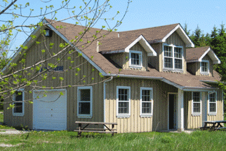 Large wooden building with several windows, man door and garage door. 